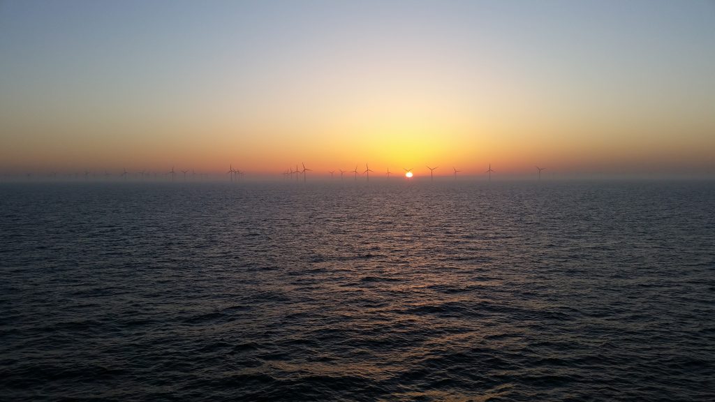 Un champ d'éolienne en mer avec un coucher de soleil